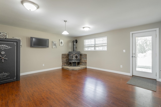 unfurnished living room with a wood stove and dark wood-type flooring