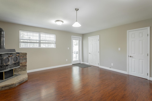 living room with dark hardwood / wood-style flooring, a wealth of natural light, and a wood stove