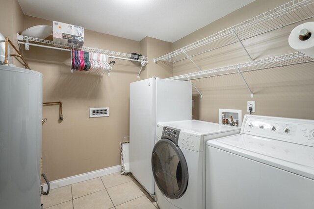 laundry room featuring water heater, washer and dryer, and light tile patterned flooring