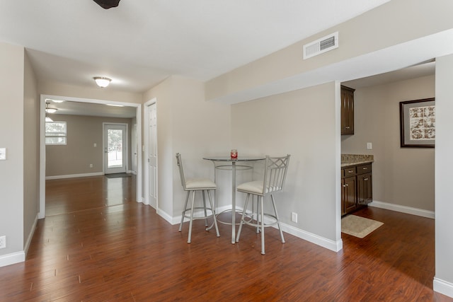 kitchen featuring dark wood-type flooring, a kitchen bar, ceiling fan, and dark brown cabinetry