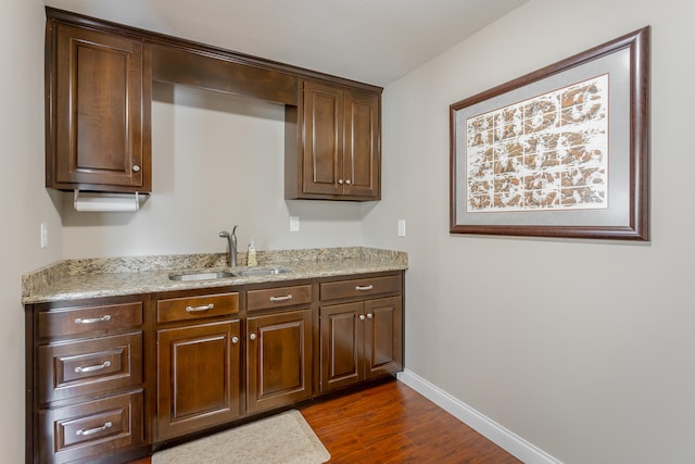 kitchen featuring light stone countertops, dark hardwood / wood-style floors, and sink