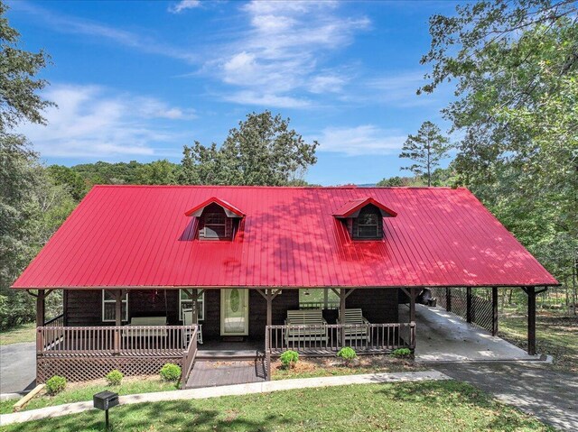 cape cod-style house featuring covered porch and a carport