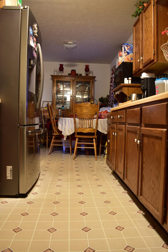 kitchen with a textured ceiling and stainless steel fridge