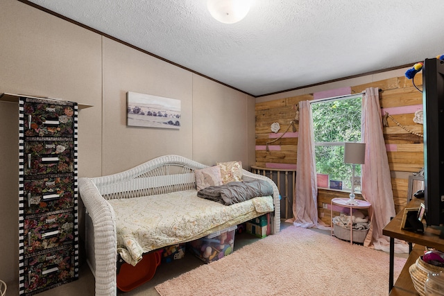 bedroom with a textured ceiling, wooden walls, ornamental molding, and carpet