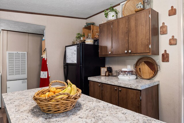 kitchen with black fridge, ornamental molding, dark brown cabinets, a textured ceiling, and hardwood / wood-style flooring