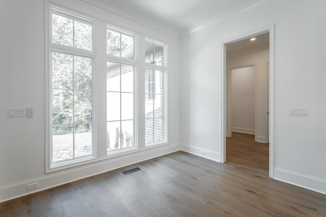 unfurnished room with a wealth of natural light, hardwood / wood-style floors, and crown molding