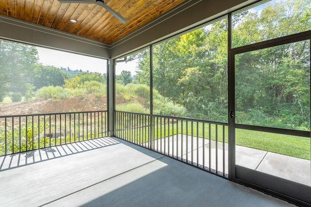 unfurnished sunroom featuring ceiling fan, wood ceiling, and a healthy amount of sunlight