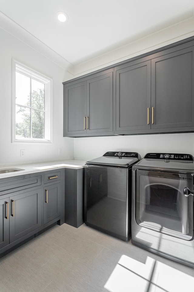 washroom featuring cabinets, sink, ornamental molding, and washing machine and dryer