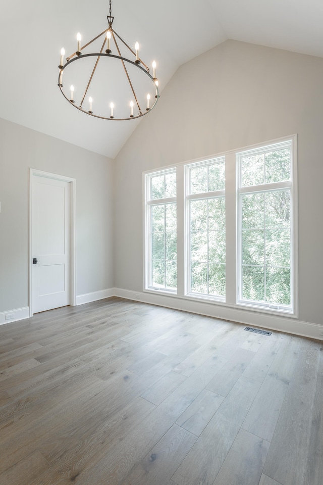 unfurnished room with a notable chandelier, wood-type flooring, and lofted ceiling