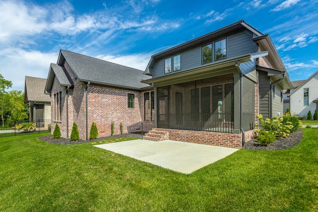 rear view of property with a sunroom, a lawn, and a patio area