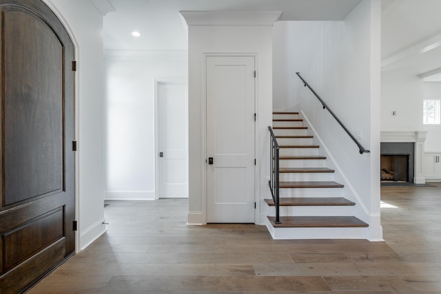 stairs featuring crown molding and hardwood / wood-style flooring