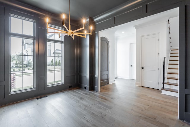 spare room featuring an inviting chandelier and light hardwood / wood-style floors