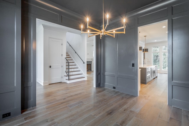 basement with sink, a chandelier, and light hardwood / wood-style floors