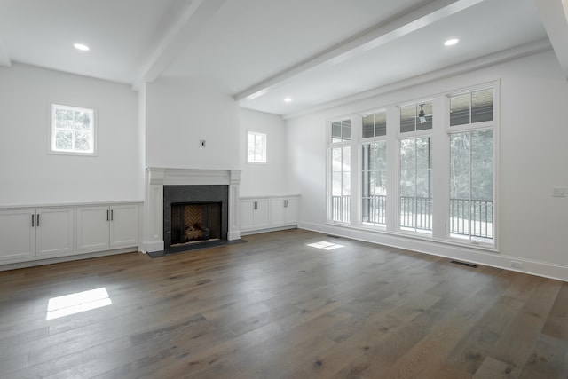 unfurnished living room featuring a fireplace, beam ceiling, dark hardwood / wood-style flooring, and a wealth of natural light