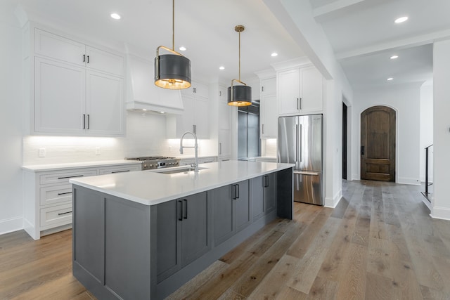 kitchen with white cabinets, sink, a center island with sink, light hardwood / wood-style flooring, and stainless steel appliances