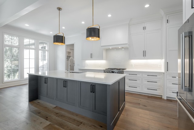 kitchen with an island with sink, white cabinets, and sink