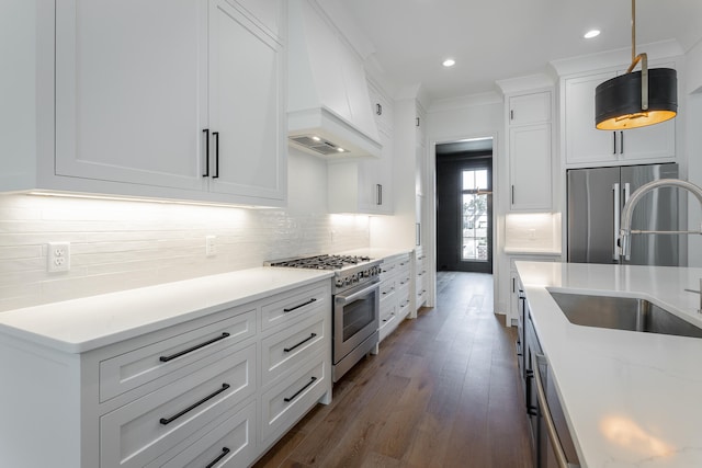 kitchen with hanging light fixtures, sink, white cabinetry, high quality appliances, and dark hardwood / wood-style flooring