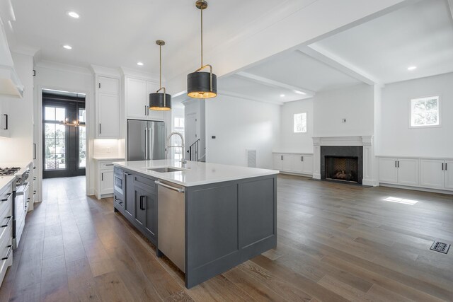 kitchen with a center island with sink, appliances with stainless steel finishes, dark hardwood / wood-style floors, and a healthy amount of sunlight