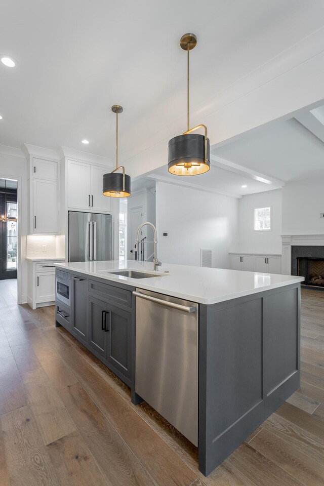 kitchen with gray cabinets, white cabinets, a kitchen island with sink, and built in appliances