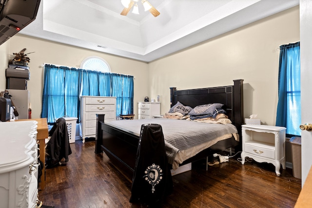 bedroom featuring dark hardwood / wood-style floors, ceiling fan, and a tray ceiling