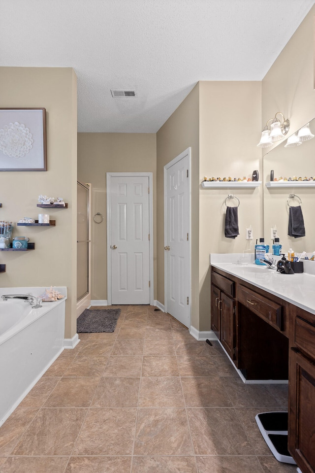 bathroom with tile patterned flooring, vanity, separate shower and tub, and a textured ceiling