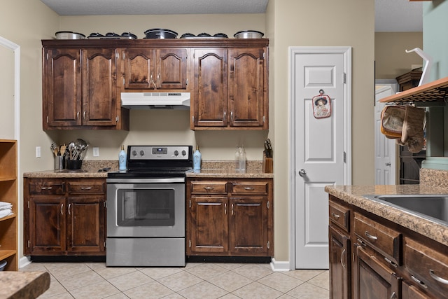 kitchen featuring stainless steel electric range, light tile patterned flooring, and dark brown cabinets