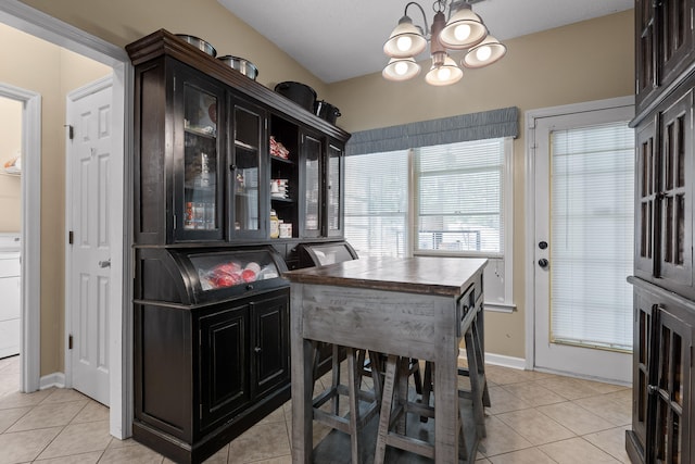 tiled dining area featuring washer / clothes dryer and an inviting chandelier