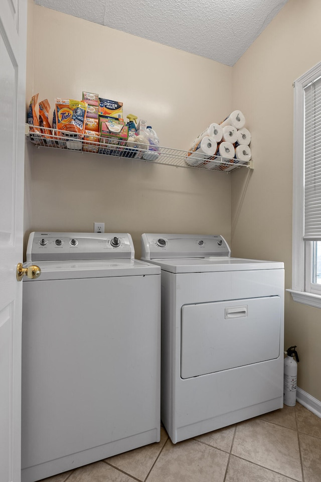 laundry area with light tile patterned floors, a textured ceiling, and washing machine and clothes dryer