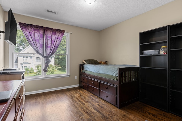 bedroom with a textured ceiling and dark hardwood / wood-style floors