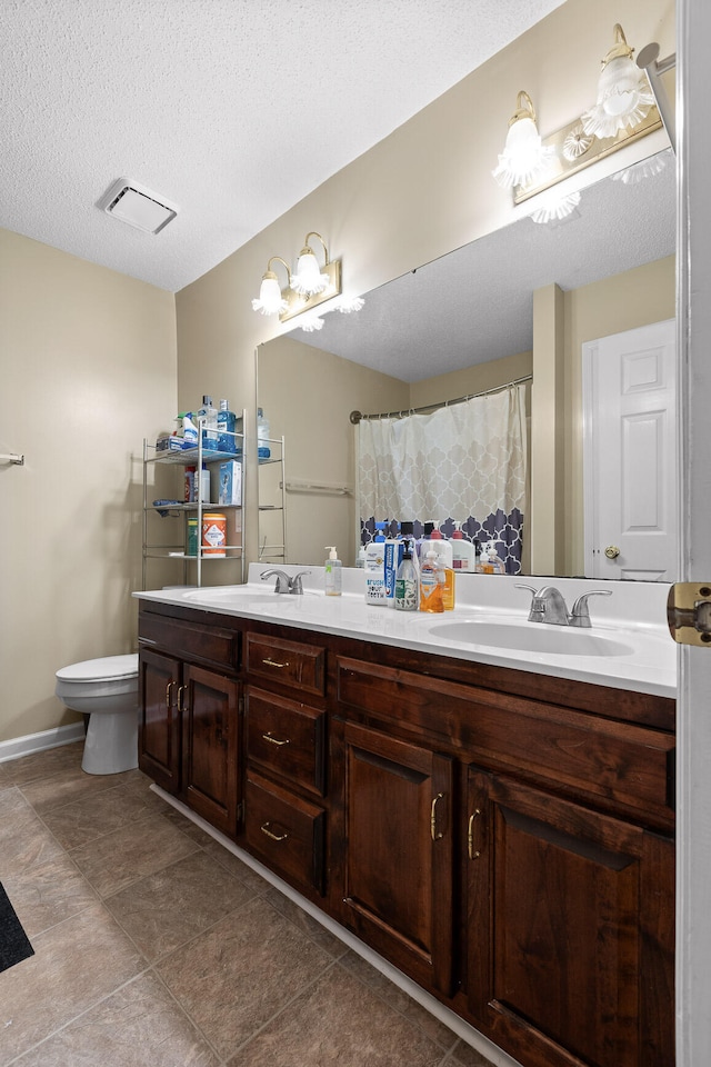 bathroom with tile patterned floors, vanity, a textured ceiling, and toilet