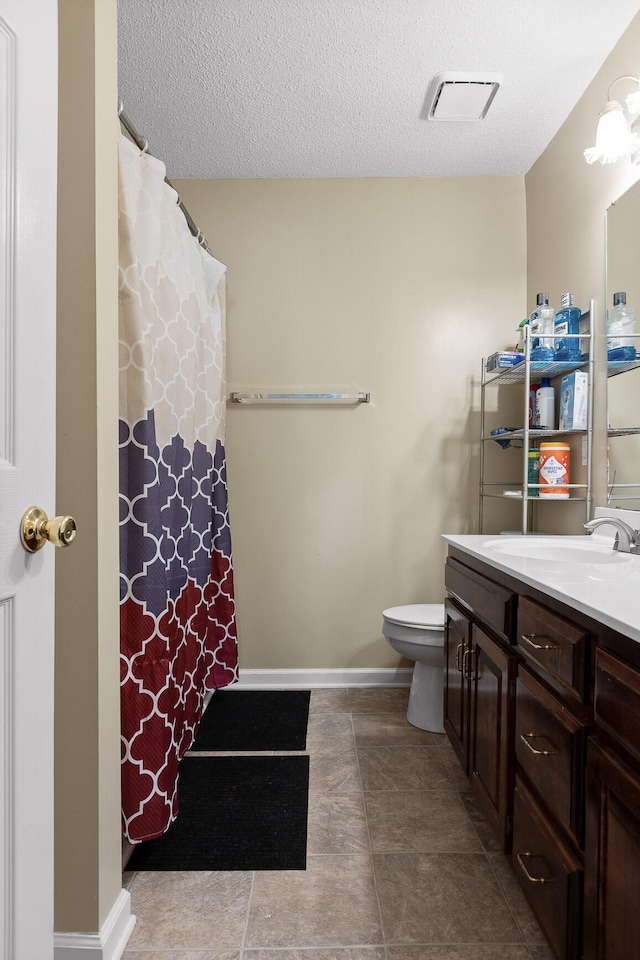 bathroom featuring vanity, toilet, and a textured ceiling