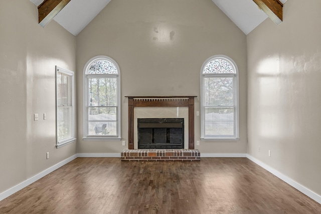 unfurnished living room featuring beamed ceiling, dark hardwood / wood-style floors, a fireplace, and high vaulted ceiling