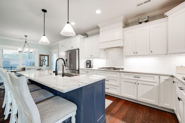 kitchen featuring decorative light fixtures, a center island with sink, a chandelier, white cabinetry, and appliances with stainless steel finishes