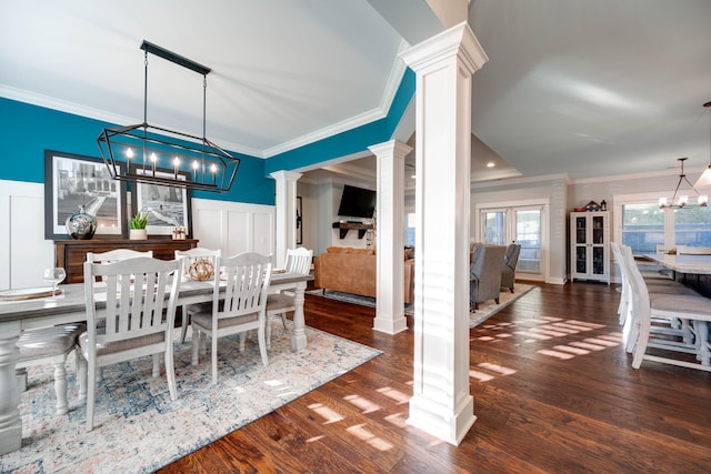 dining area with ornamental molding, decorative columns, a notable chandelier, and dark hardwood / wood-style flooring