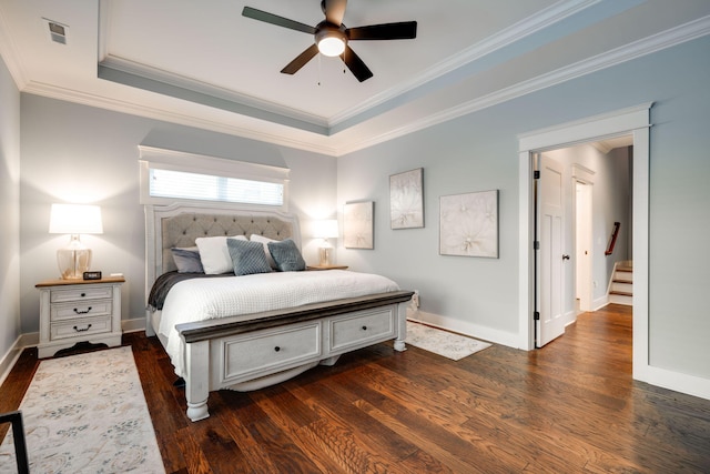 bedroom featuring a raised ceiling, ornamental molding, ceiling fan, and dark wood-type flooring