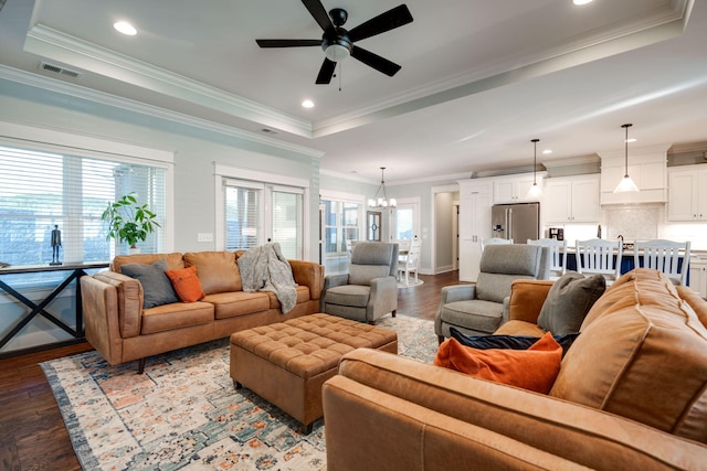 living room featuring ceiling fan with notable chandelier, a raised ceiling, and hardwood / wood-style floors