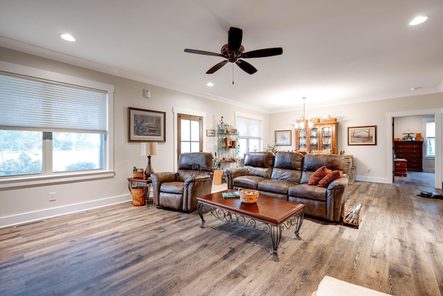 living room with ceiling fan with notable chandelier, light hardwood / wood-style floors, and crown molding