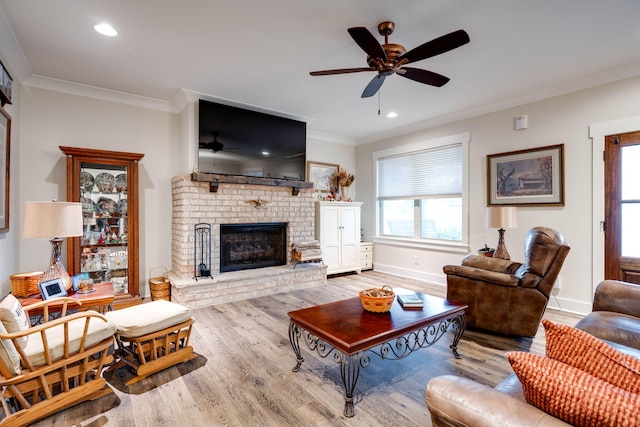 living room with wood-type flooring, ornamental molding, ceiling fan, and a brick fireplace