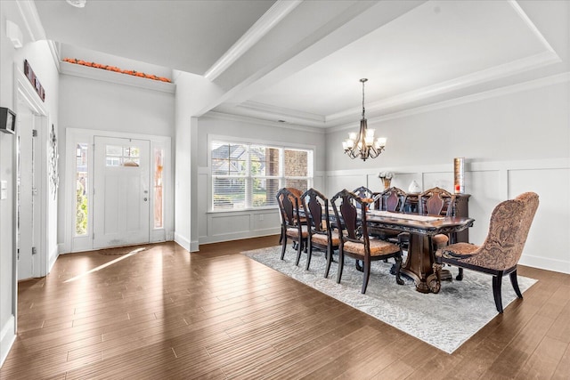 dining space with ornamental molding, dark hardwood / wood-style floors, a tray ceiling, and a notable chandelier