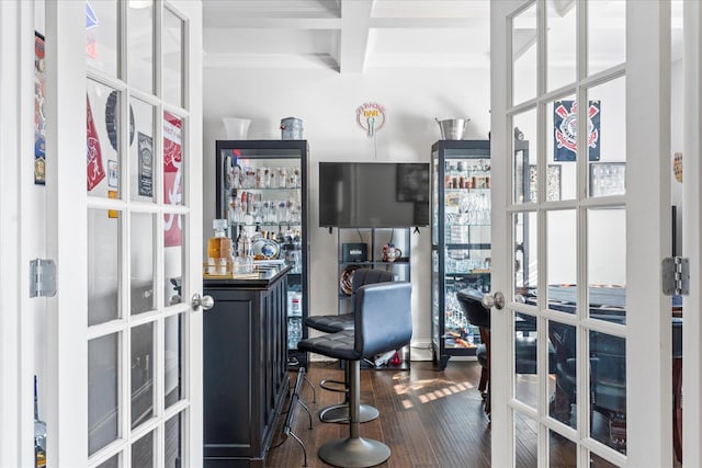 office space featuring dark wood-type flooring, beamed ceiling, a healthy amount of sunlight, and bar area