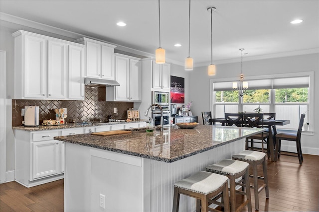 kitchen with white cabinets, dark hardwood / wood-style floors, and an island with sink