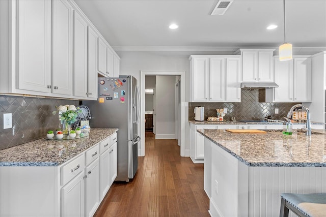 kitchen featuring pendant lighting, tasteful backsplash, dark hardwood / wood-style flooring, light stone counters, and white cabinets