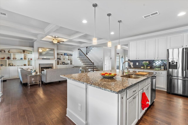 kitchen featuring a tiled fireplace, a center island with sink, appliances with stainless steel finishes, sink, and white cabinets