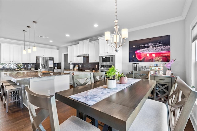 dining space with dark wood-type flooring, an inviting chandelier, and ornamental molding