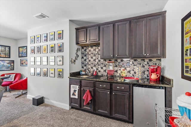 kitchen featuring light colored carpet, dark stone countertops, decorative backsplash, and dark brown cabinets