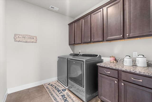 clothes washing area featuring dark tile patterned floors, cabinets, and washing machine and dryer