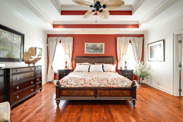 bedroom featuring multiple windows, ornamental molding, and a tray ceiling