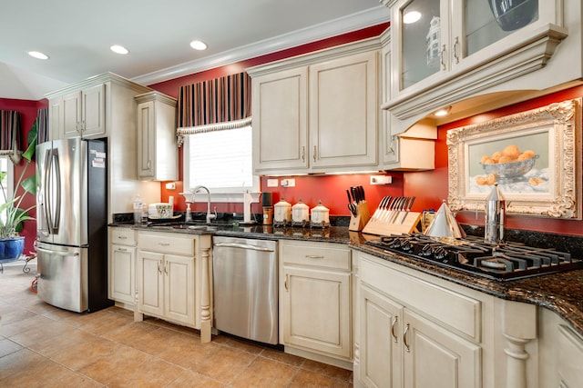 kitchen featuring dark stone counters, appliances with stainless steel finishes, and cream cabinetry