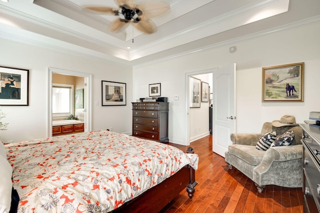 bedroom with a tray ceiling, dark wood-type flooring, ensuite bath, ornamental molding, and ceiling fan