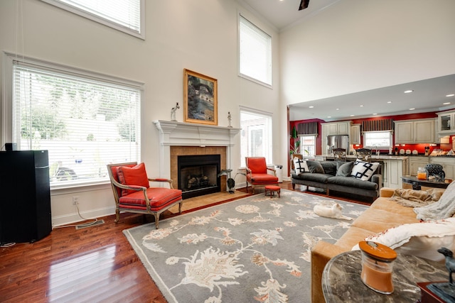 living room with ornamental molding, a towering ceiling, hardwood / wood-style flooring, and a fireplace